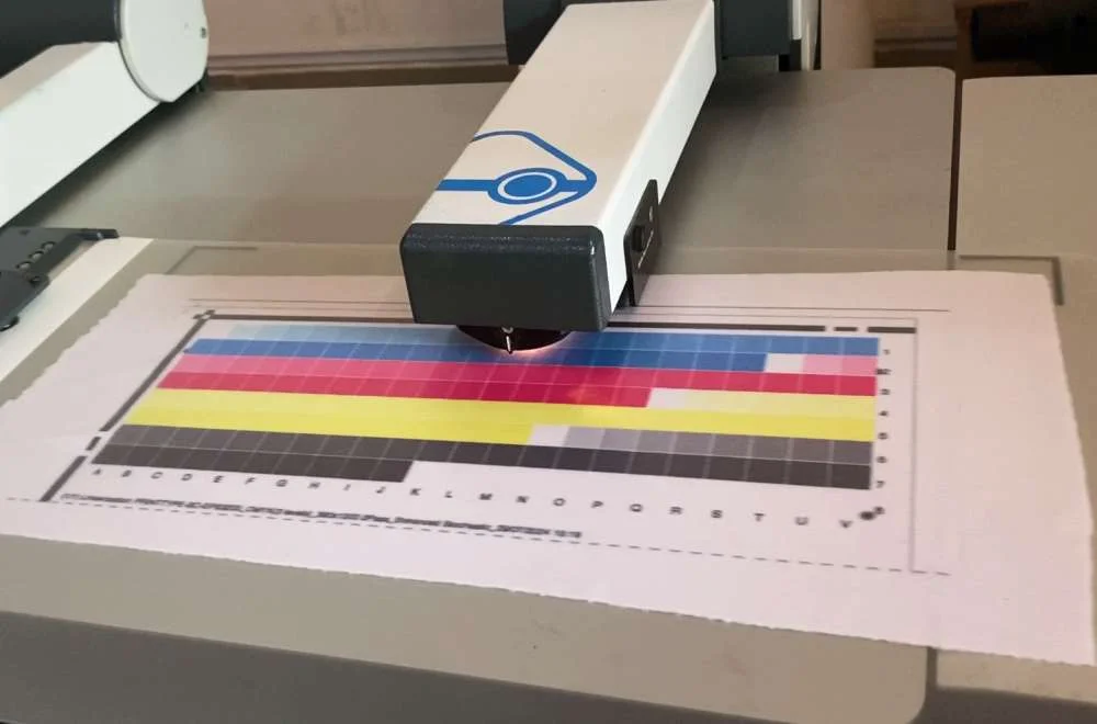 Alat kalibrasi warna sedang membaca chart warna untuk membuat ICC profile pada printer sublim agar setting printer sublim untuk jersey menghasilkan warna akurat.