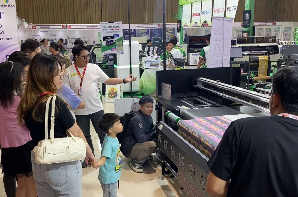Pengunjung berdiskusi sambil menyaksikan demo mesin digital printing di booth IAPE Bandung 2026.