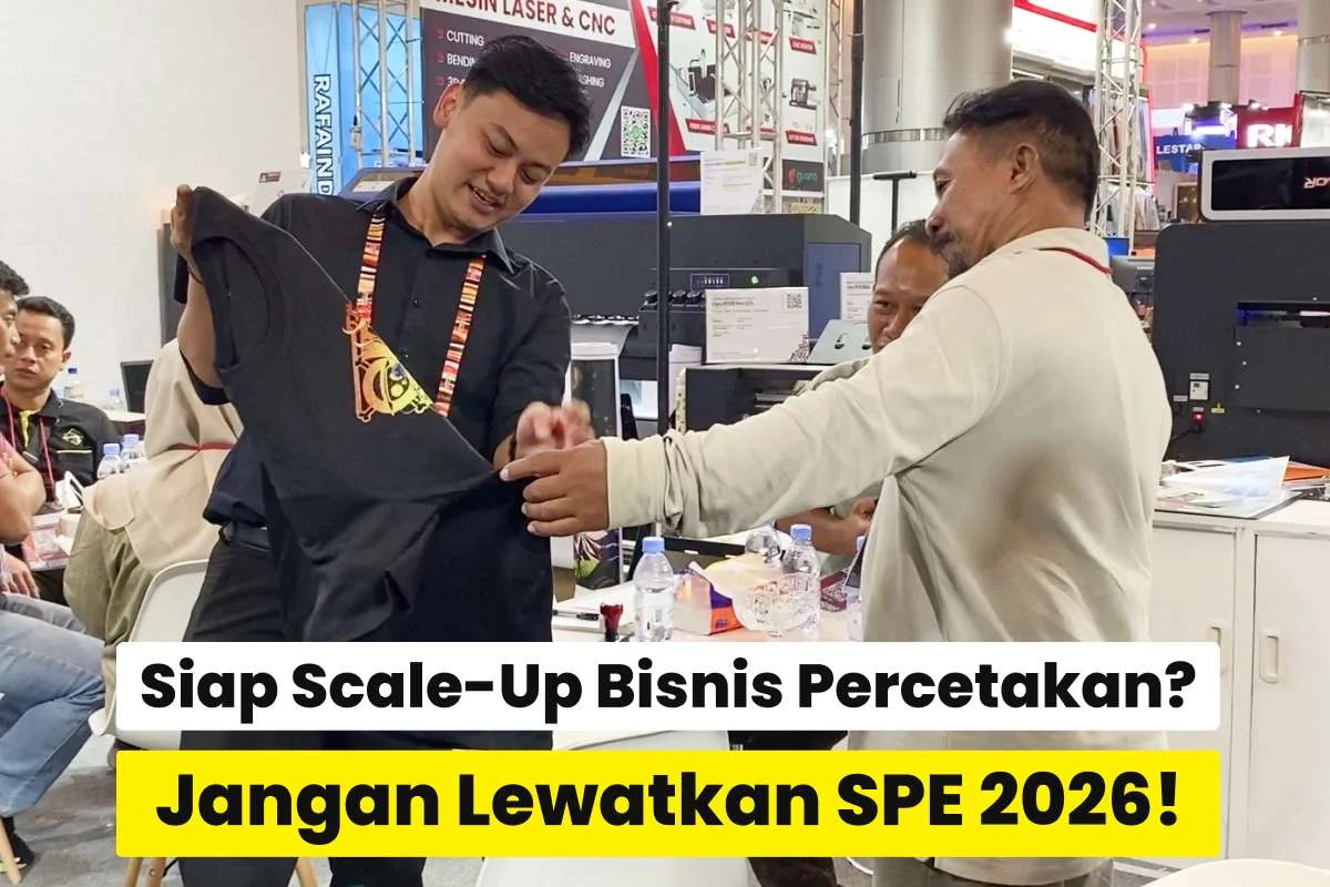 Tim exhibitor berdiskusi dengan pengunjung sambil menunjukkan hasil cetak kaos di pameran Surabaya Printing Expo 2026 sebagai solusi pengembangan bisnis percetakan.