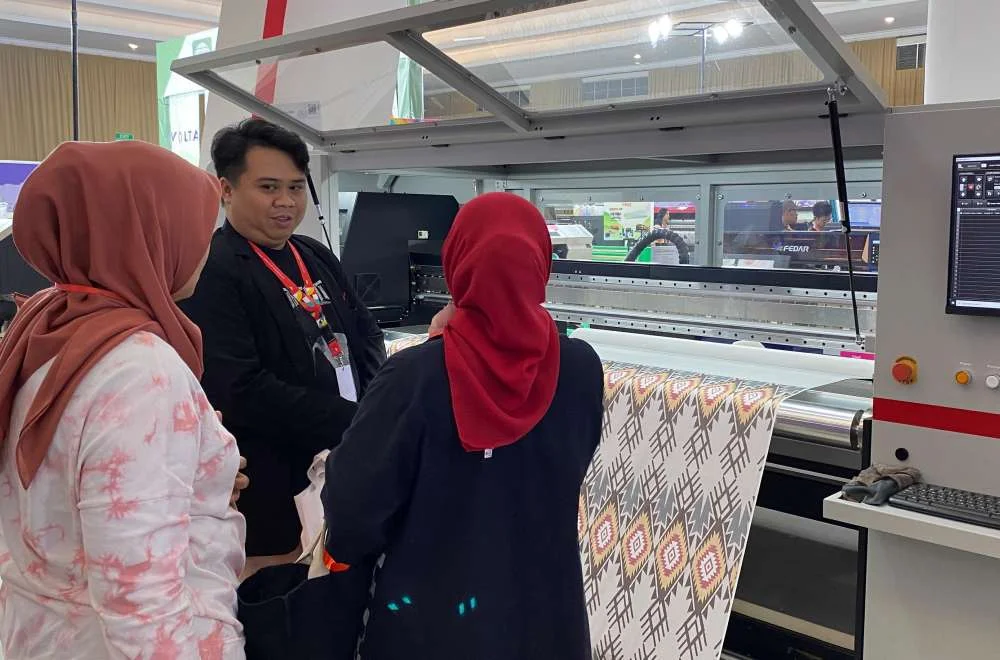 Pengunjung melihat demo mesin printing di booth Laysander pada kenduri sablon jogja 2026 bersama tim ahli Fedar Indonesia.