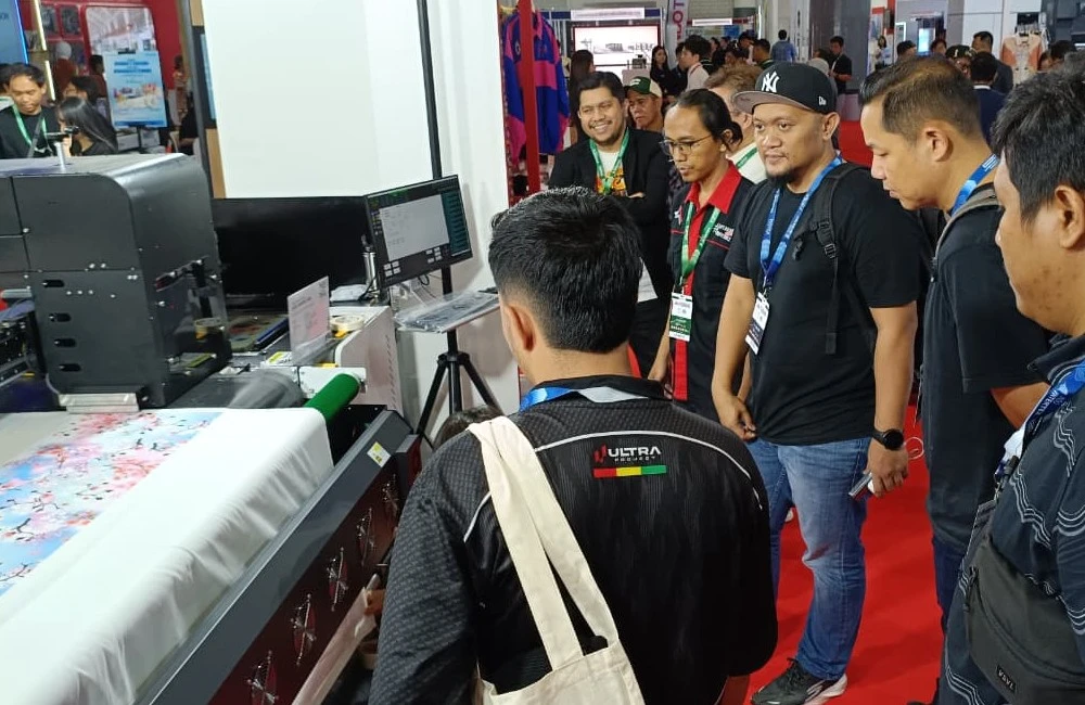 Pengunjung menyaksikan proses test print mesin digital printing bersama tim Laysander di pameran IAPE.