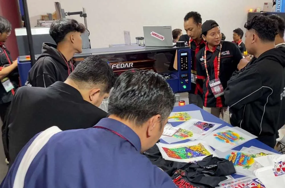 Pengunjung berdiskusi dengan tim ahli sambil melihat contoh hasil cetak dan demonstrasi mesin di pameran Surabaya Printing Expo 2026.